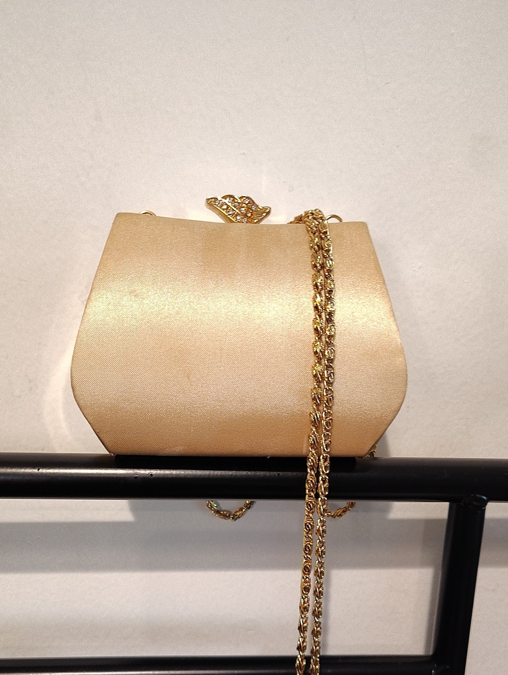 This is a gold satin Jessica McClintock clutch featuring a jeweled closure Gold